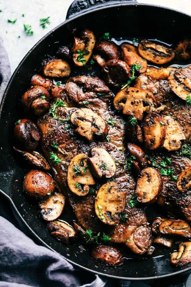 Steak with mushrooms in a skillet.