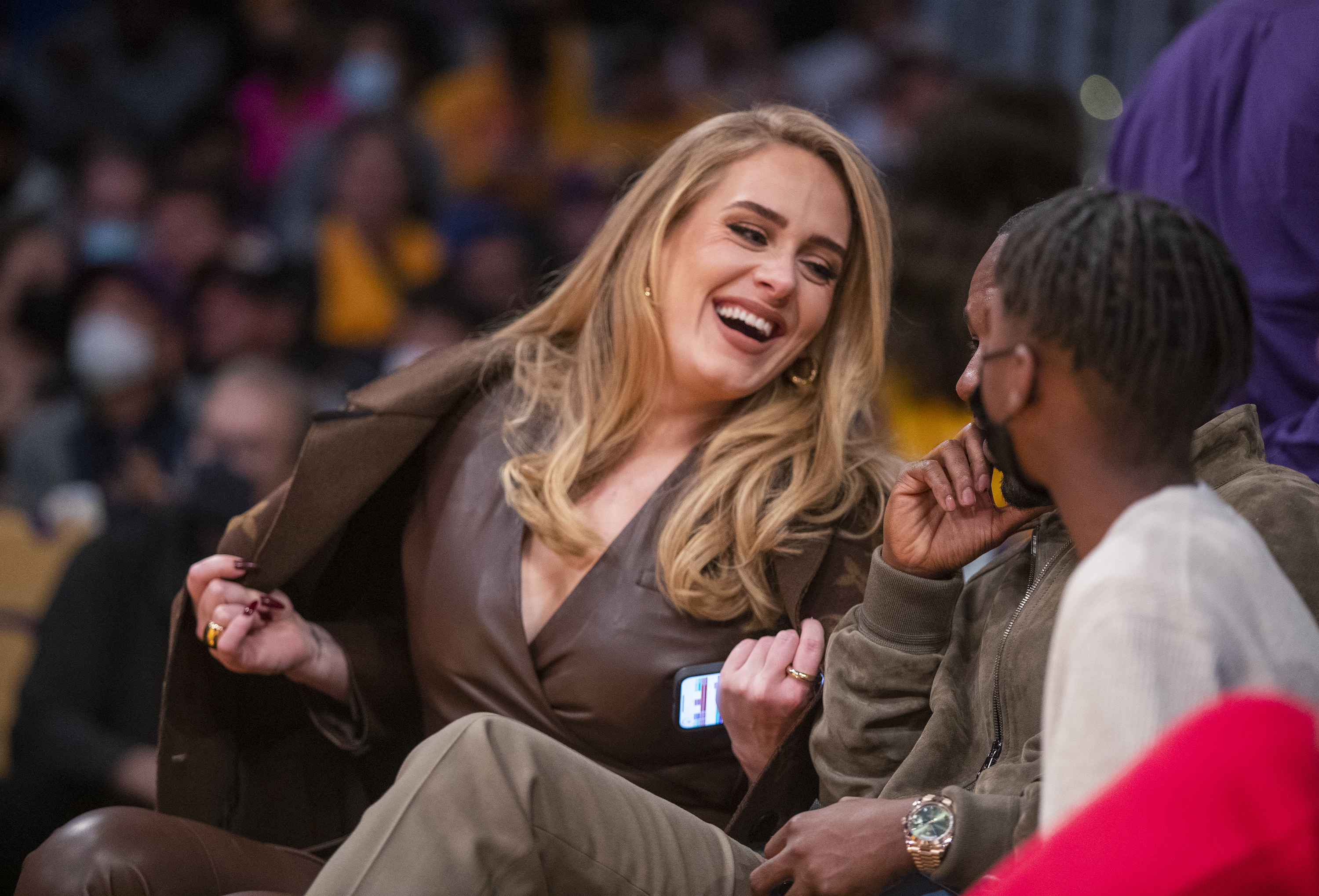 Adele laughing as talks to someone during an NBA basketball game