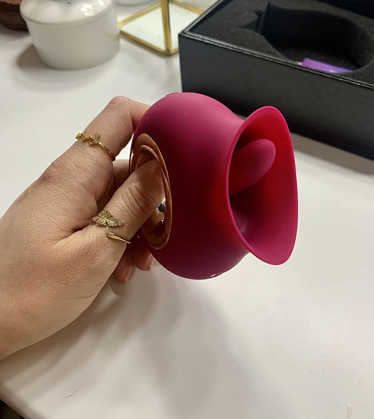 hand holding the rose shaped toy with tongue at opening and a metallic cutout handle at the base