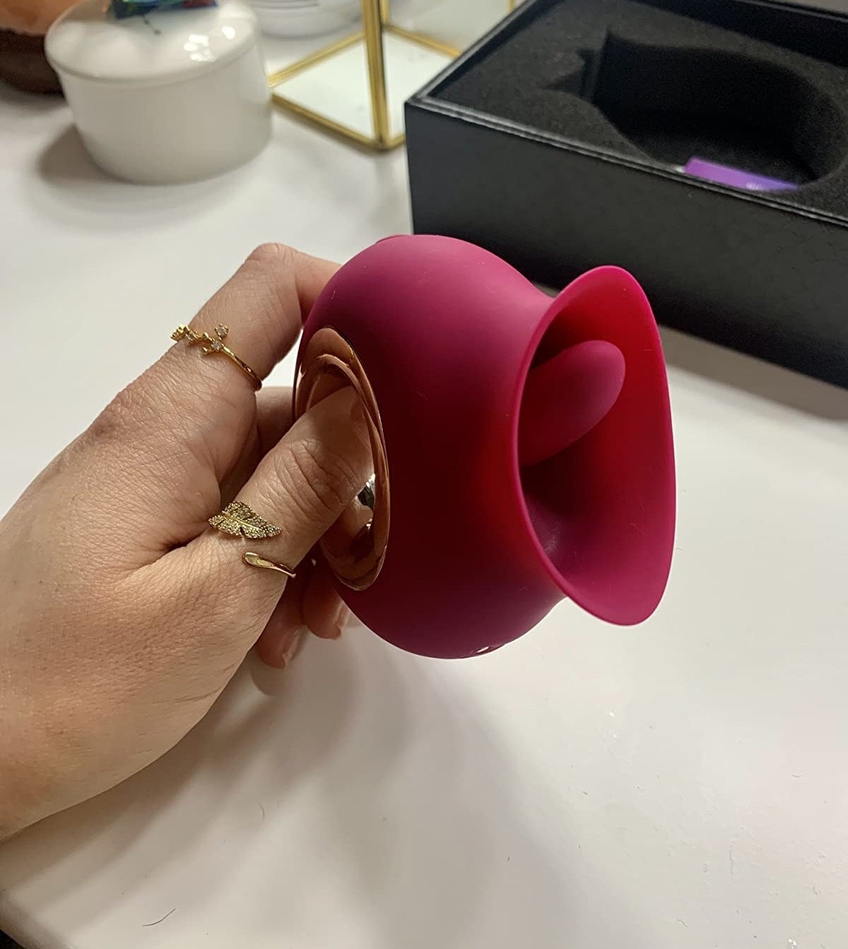 hand holding the rose shaped toy with tongue at opening and a metallic cutout handle at the base