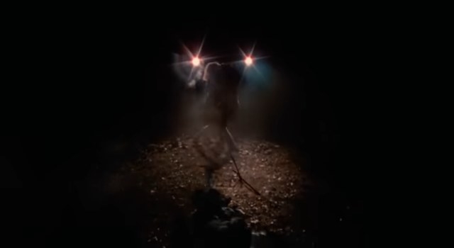 Ash and Cheryl standing in front of his car&#x27;s headlights in the dark in &quot;The Evil Dead&quot;