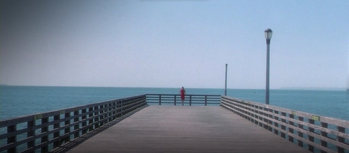 A woman in a red dress standing at a pier in "Requiem for a Dream"