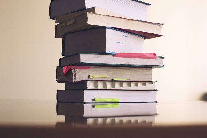 A stack of textbooks with sticky notes