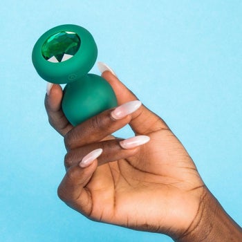 Model holding green bejeweled butt plug