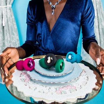 Model with plate of colorful bejeweled butt plugs