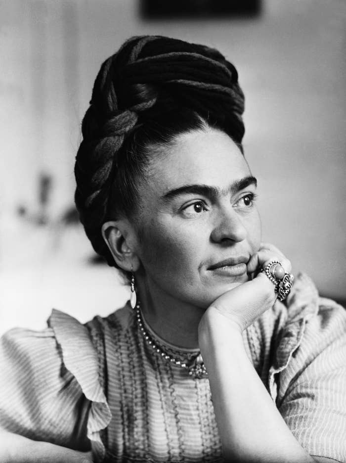 A portrait of Frida Kahlo shows her looking to the right, wearing rings on her fingers, earrings, a necklace, and her hair tied up