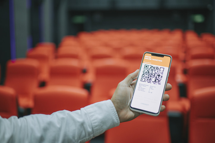 man using mobile app cinema movie e-ticketing reservation looking for seat inside cinema hall