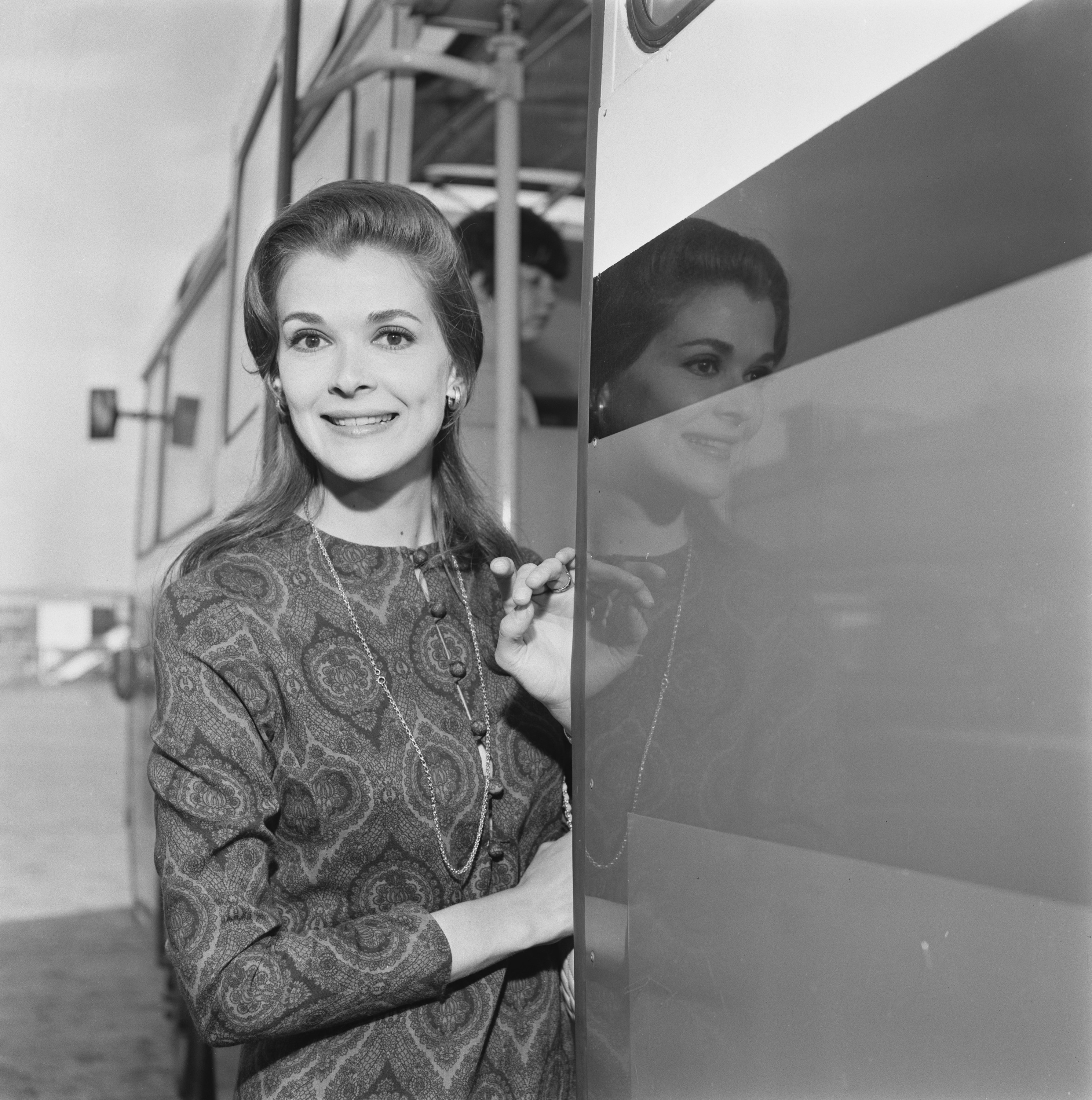 Jessica Walter in a paisley dress leaning out of a bus
