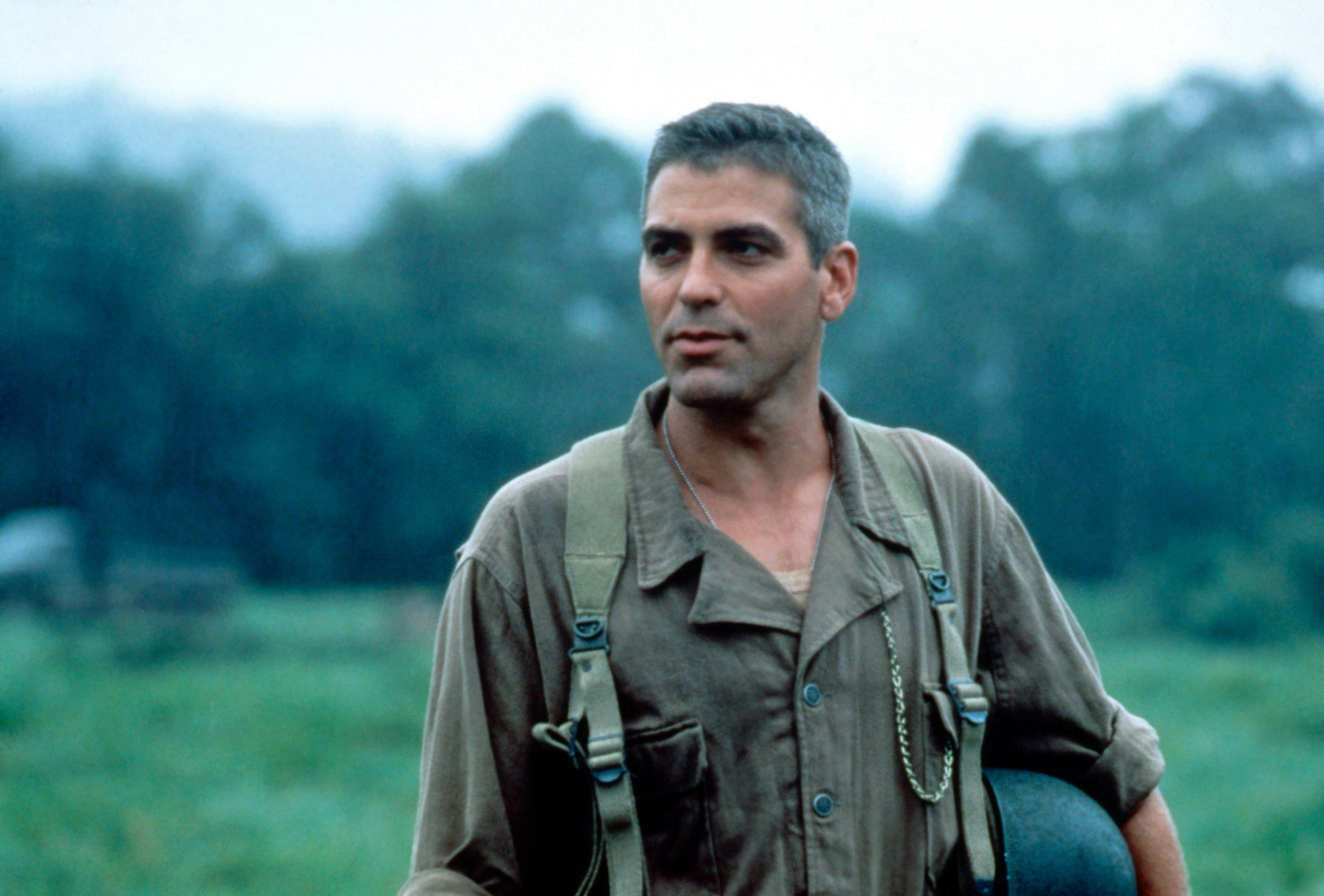 George Clooney stands in a field in an Army uniform