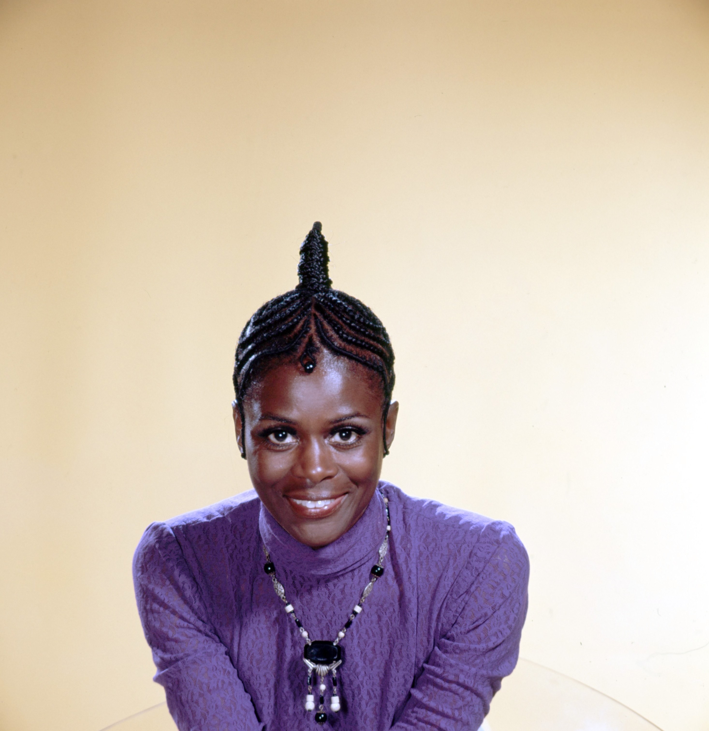 Cicely Tyson in cornrows and a turtleneck smiling at the camera