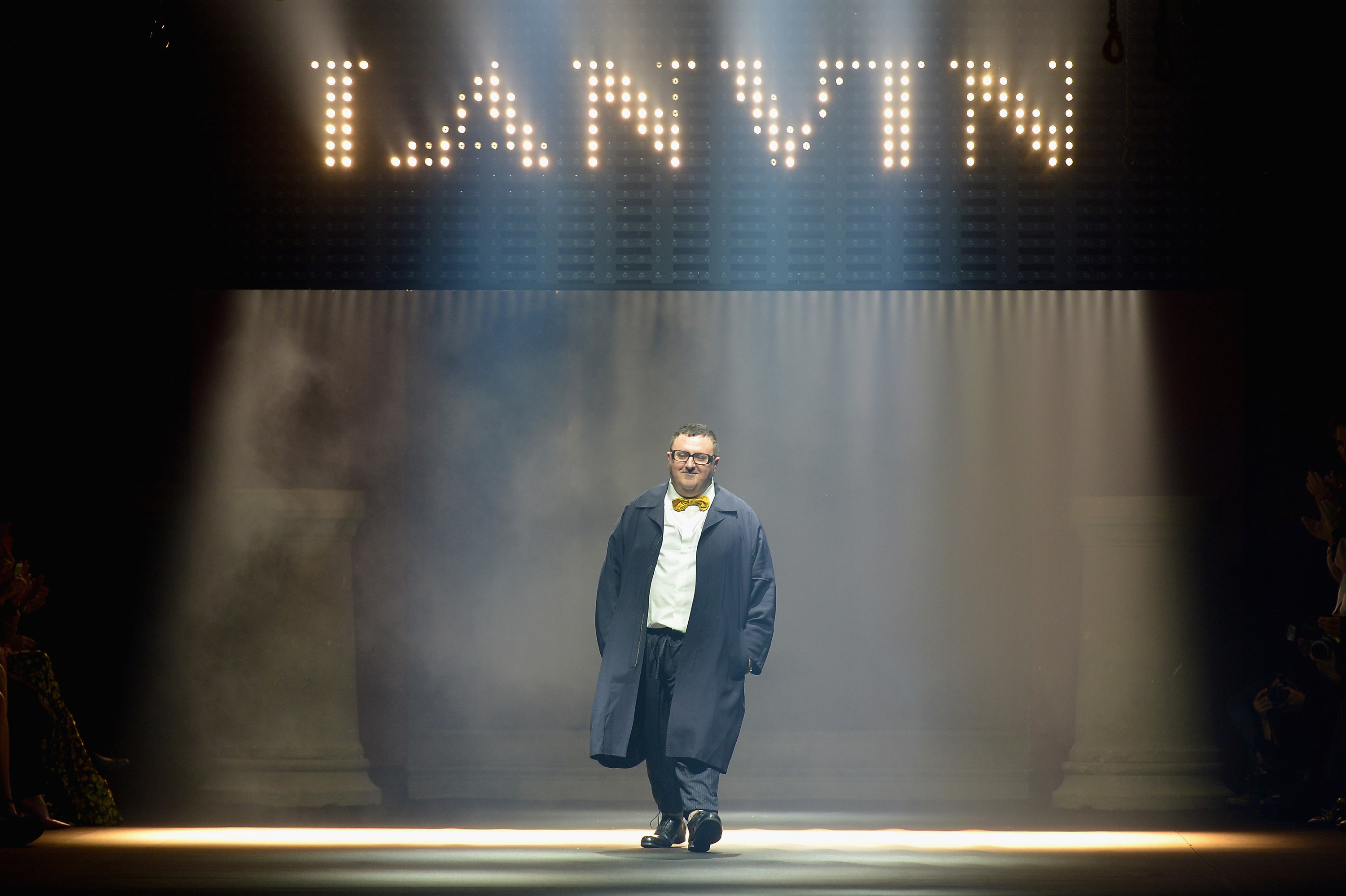 Alber Elbaz walks on a runway under a giant light-up Lanvin sign 