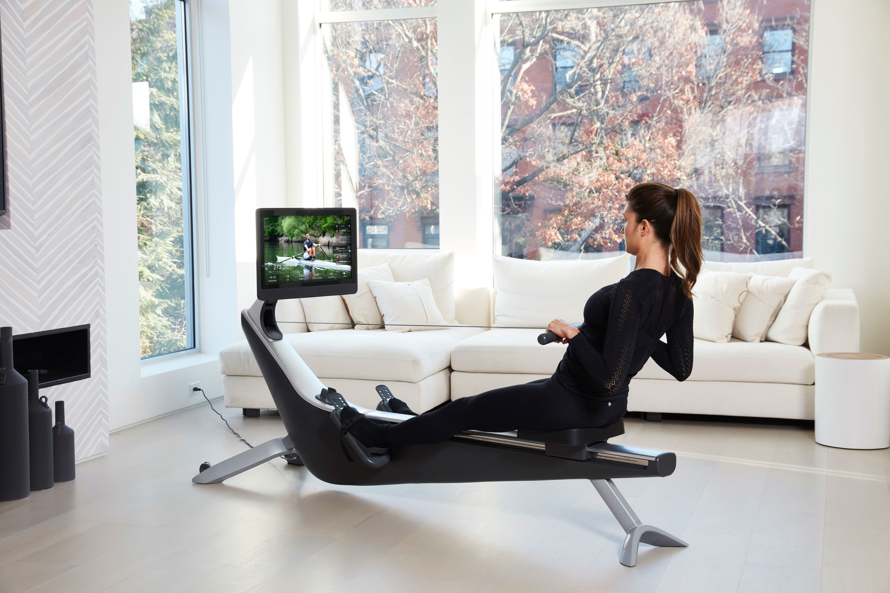 A person rowing on a Hydrow in a living room.