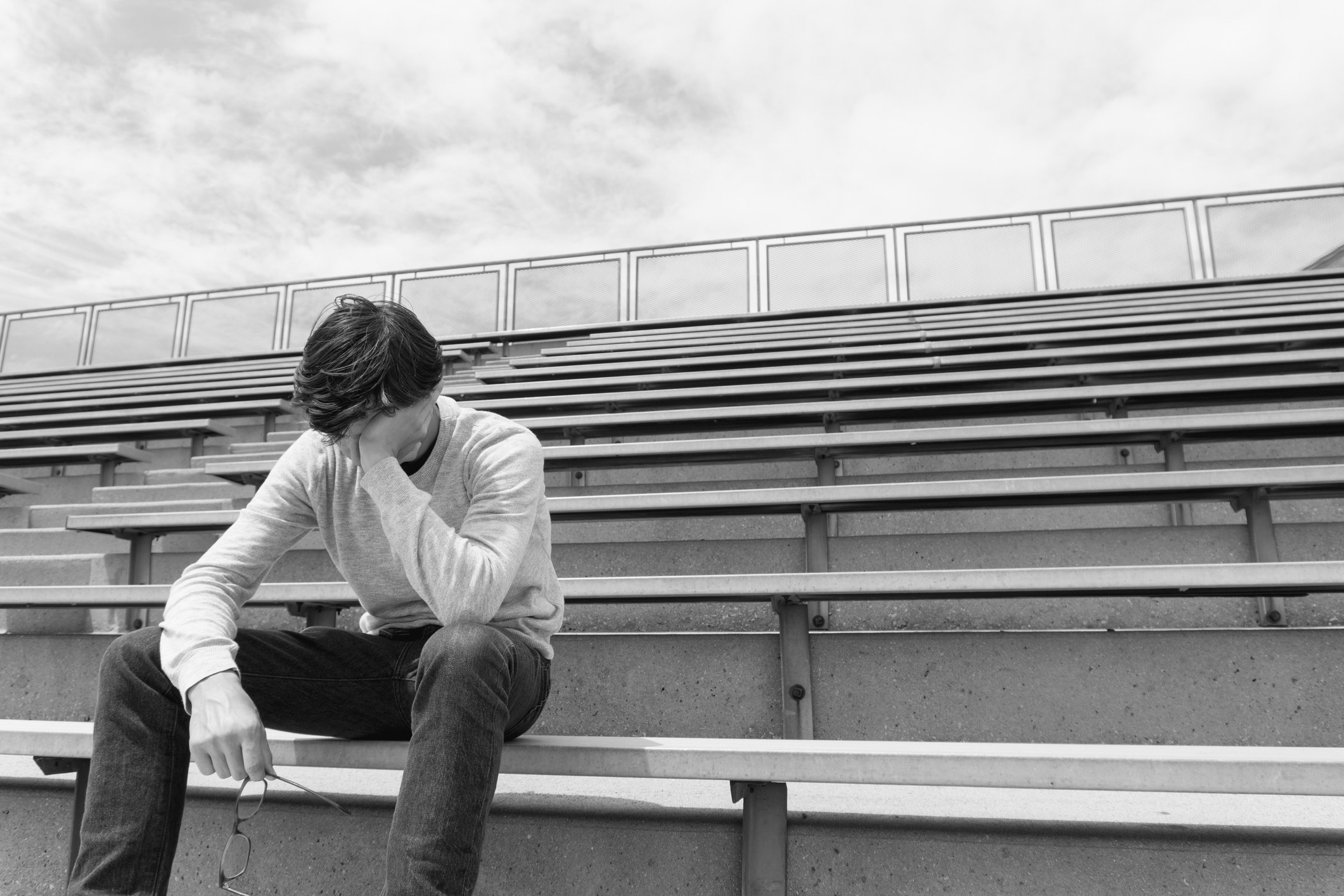 upset young man sitting on bleachers