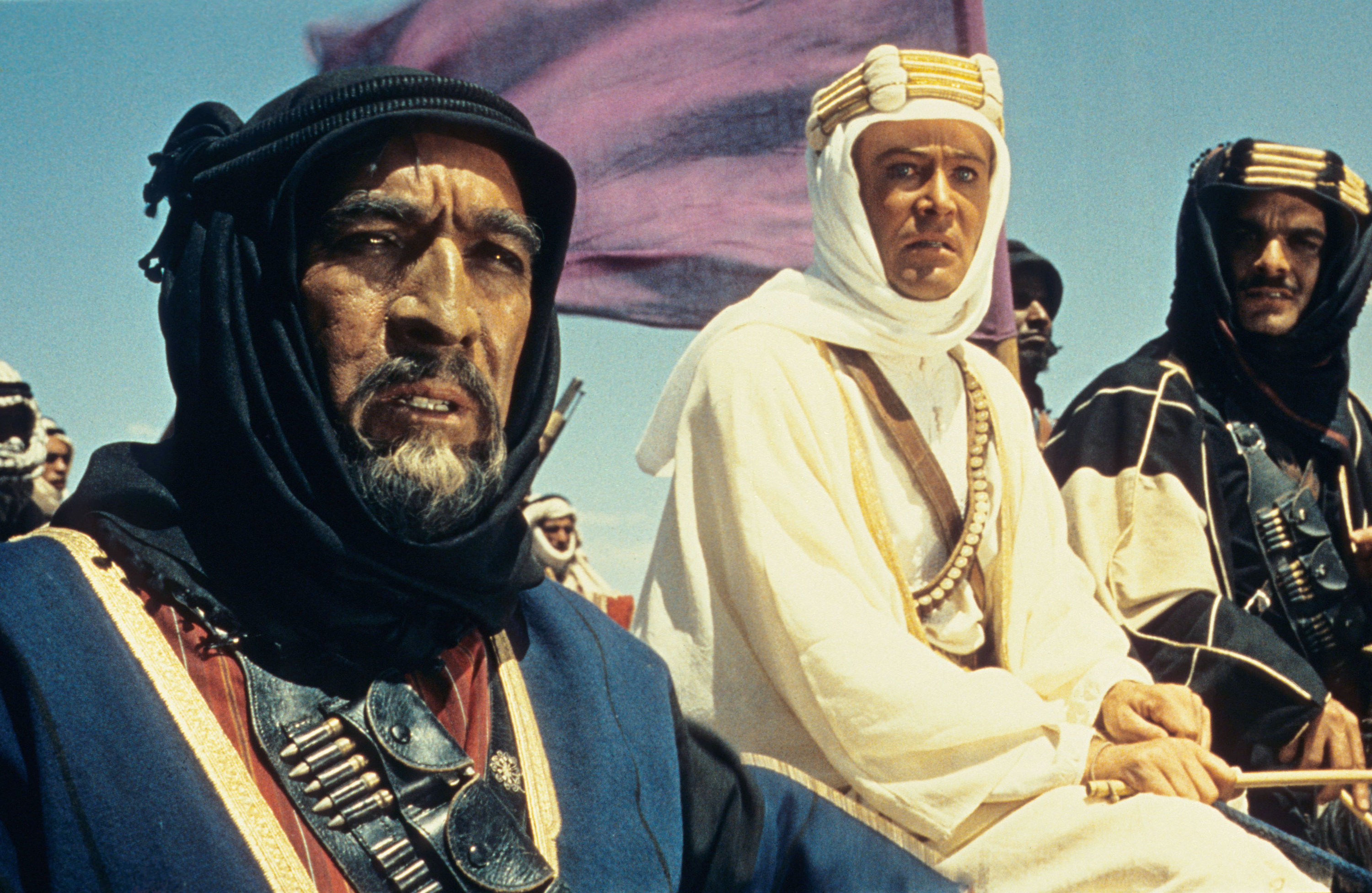 Anthony Quinn, Peter O&#x27;Toole, and Omar Sharif look off into the desert