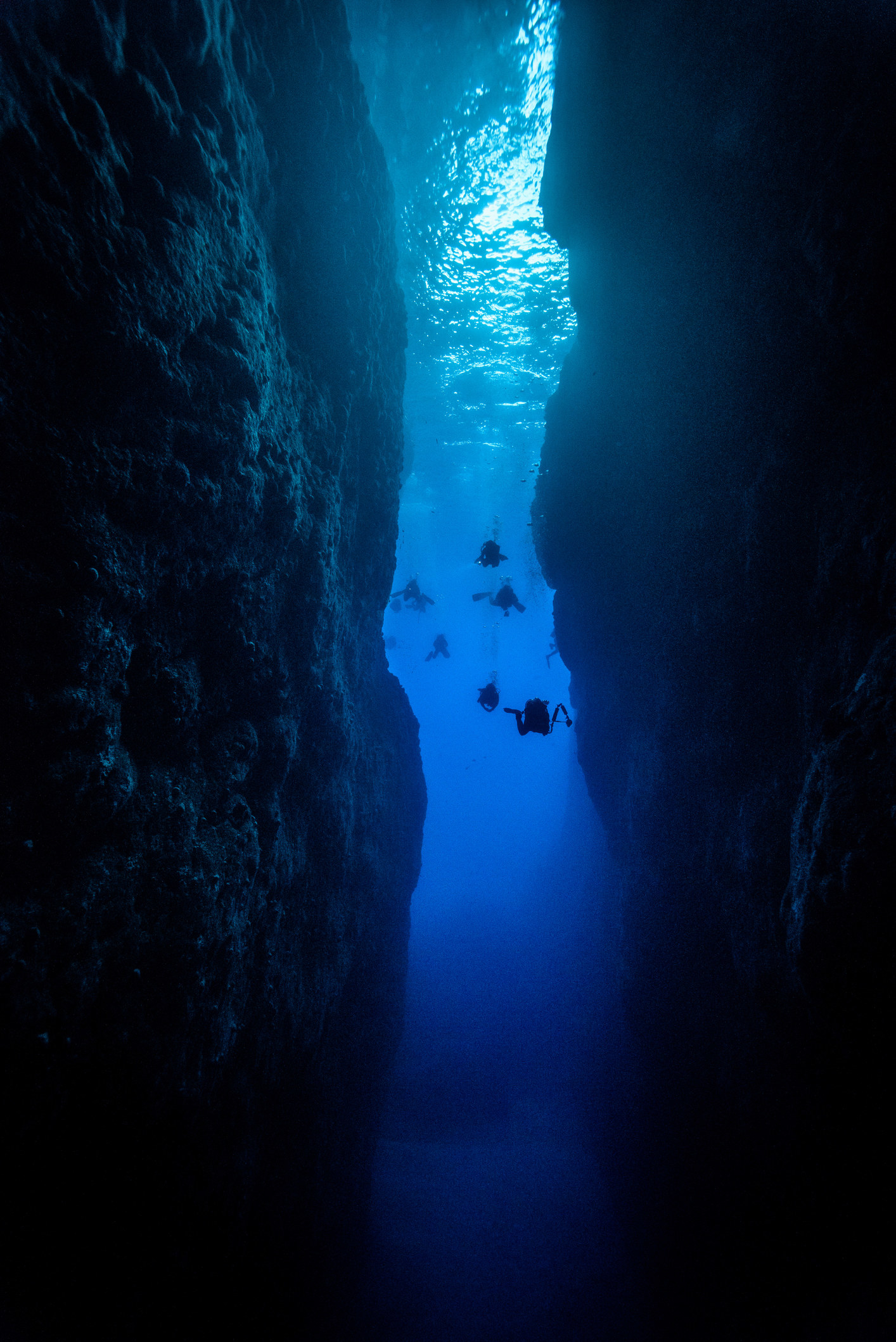 A diver diving into a dark underwater cave