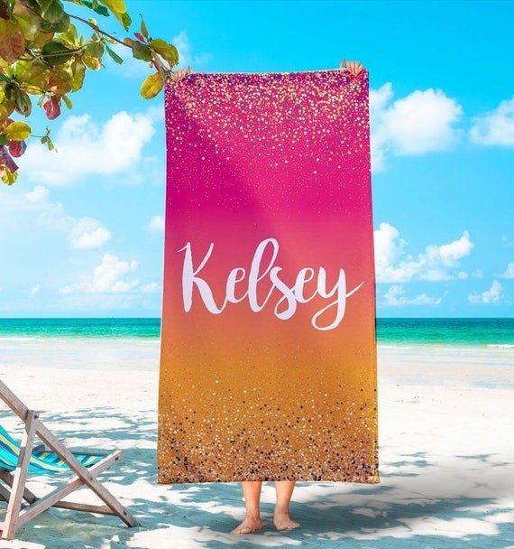 a person holding up a yellow and pink sparkling towel that says &quot;Kelsey&quot;
