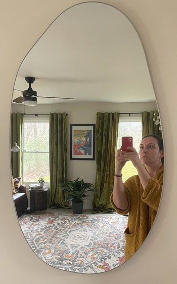 A reviewer taking a selfie in the mirror to show it's shape