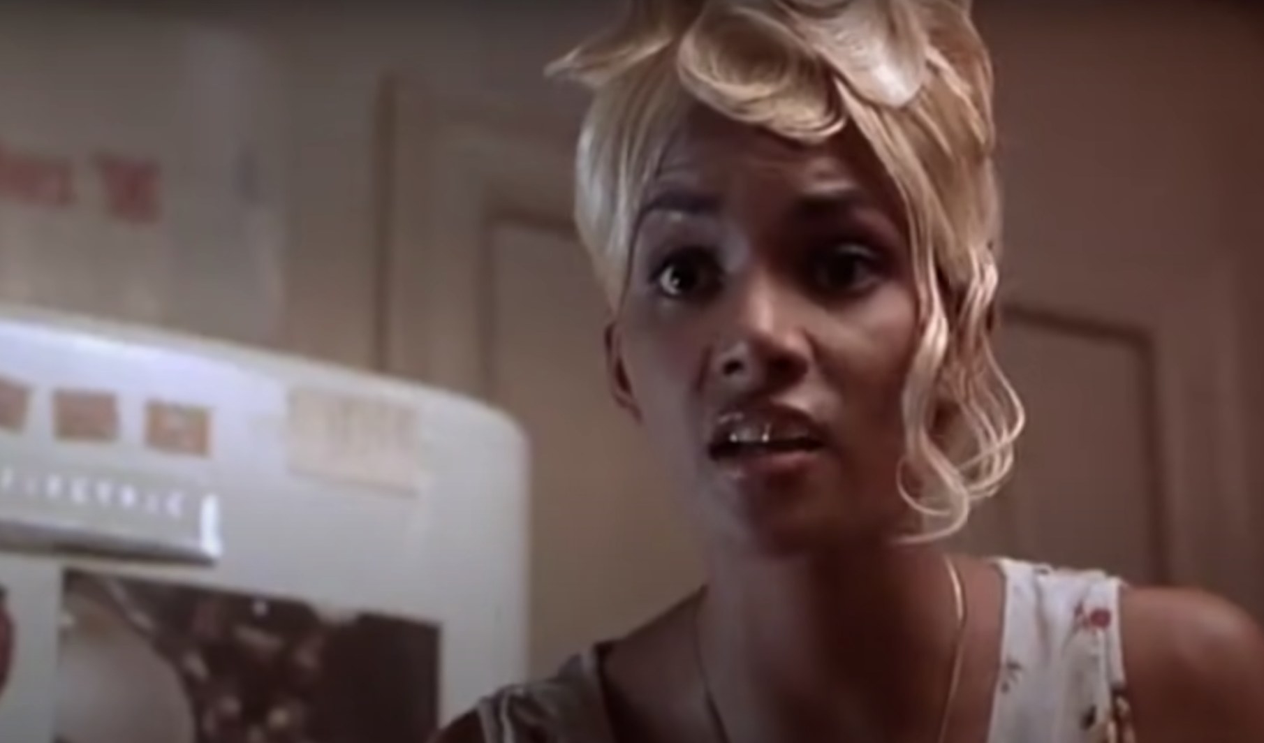 Actress Halle Berry wears a blonde wig and looks stunned at the camera.