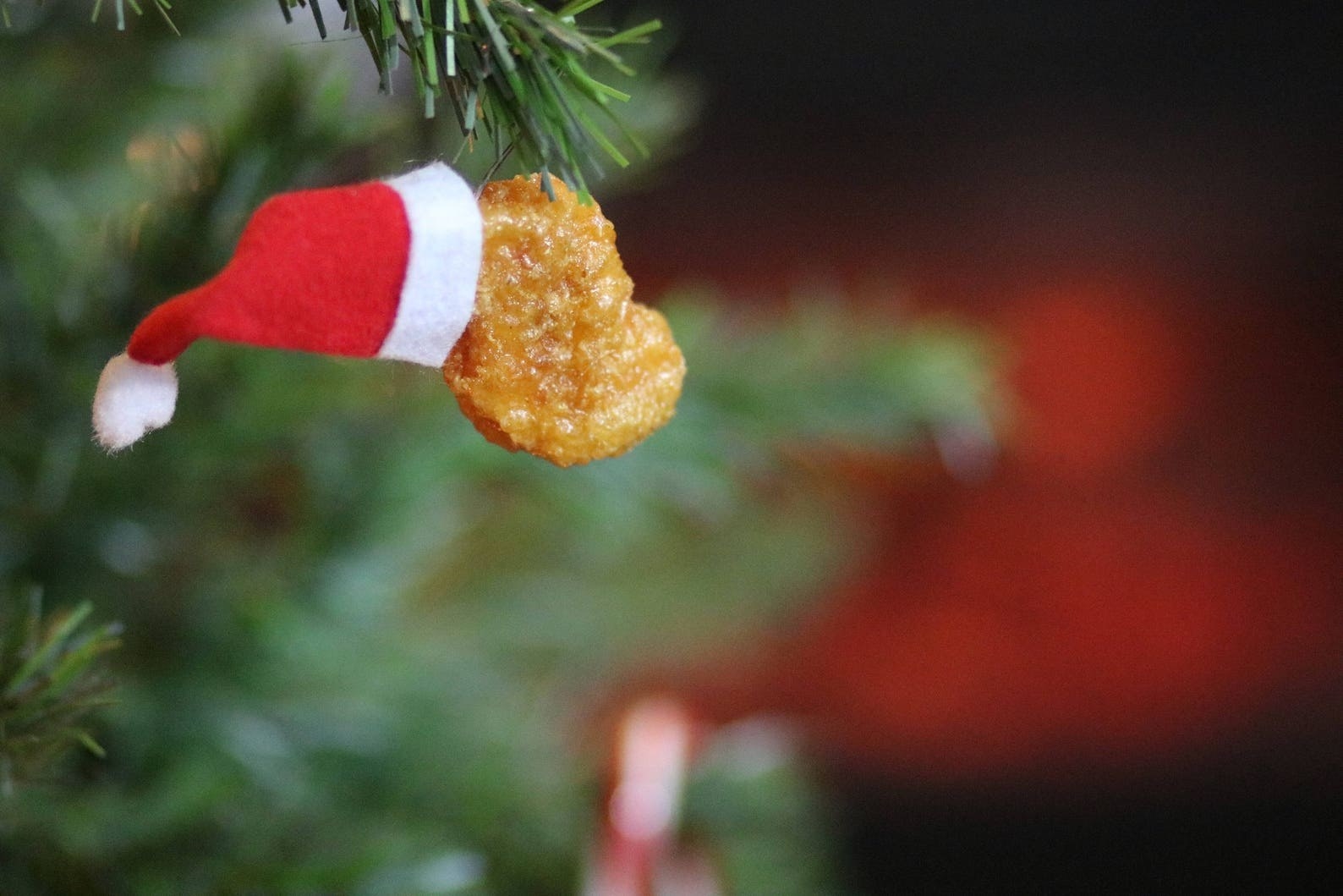 The Santa hat chicken nugget ornament hanging on a tree
