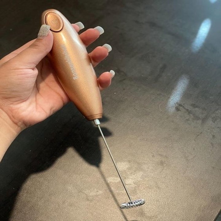 reviewer holding the slender stick milk frother