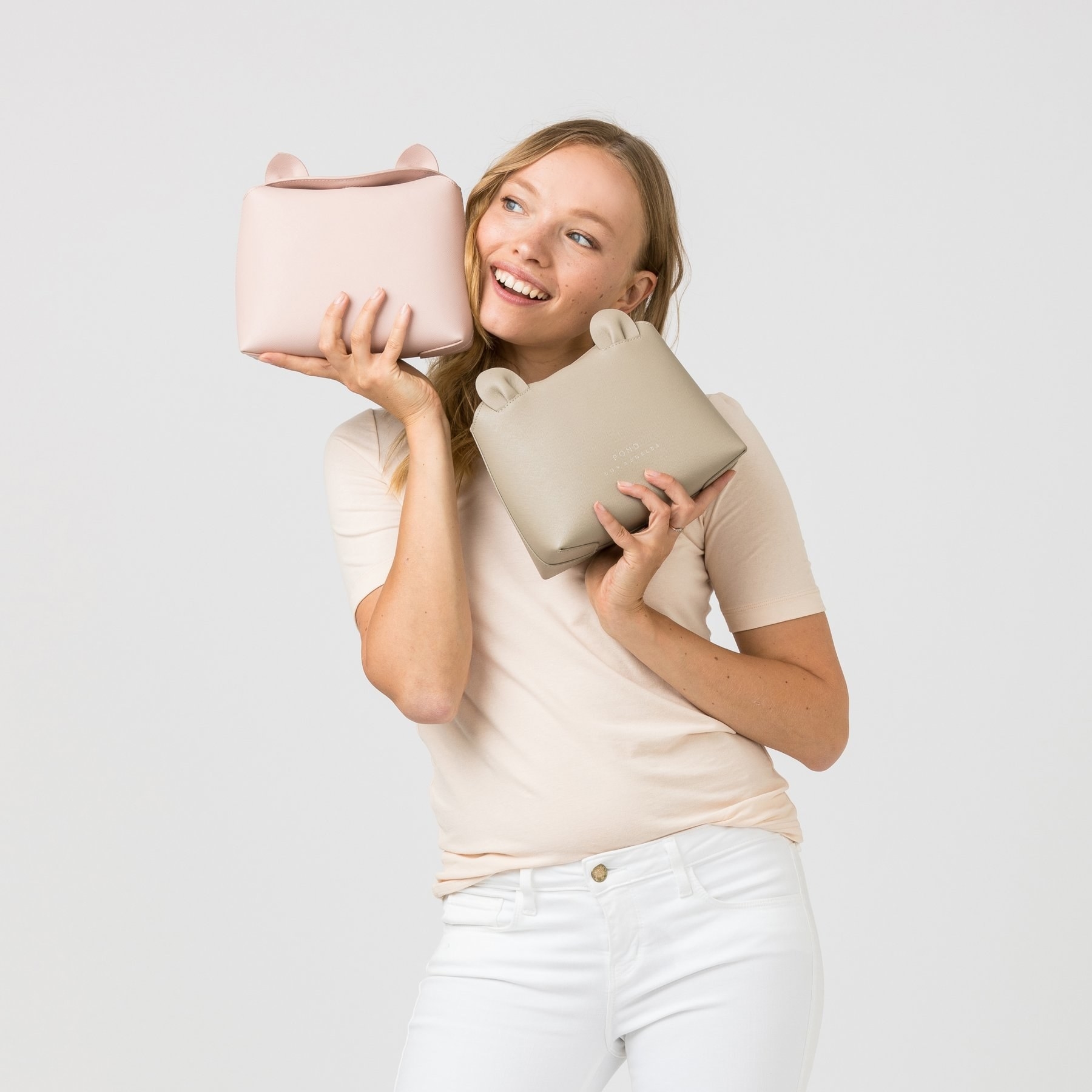 A model holding two of the crossbody bags next to her face