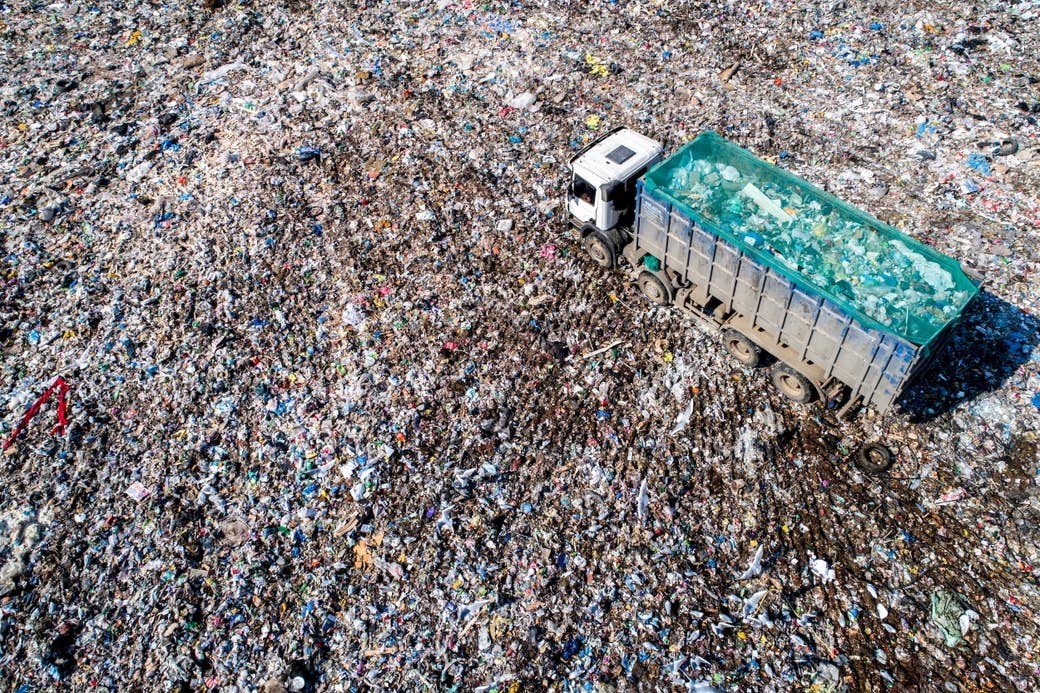 An aerial view of the Aleksinsky Karyer solid waste landfill with a truck carrying more trash driving through it

