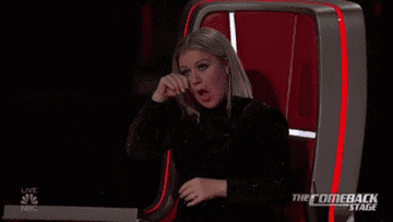 Kelly Clarkson wiping away happy ears on The Voice