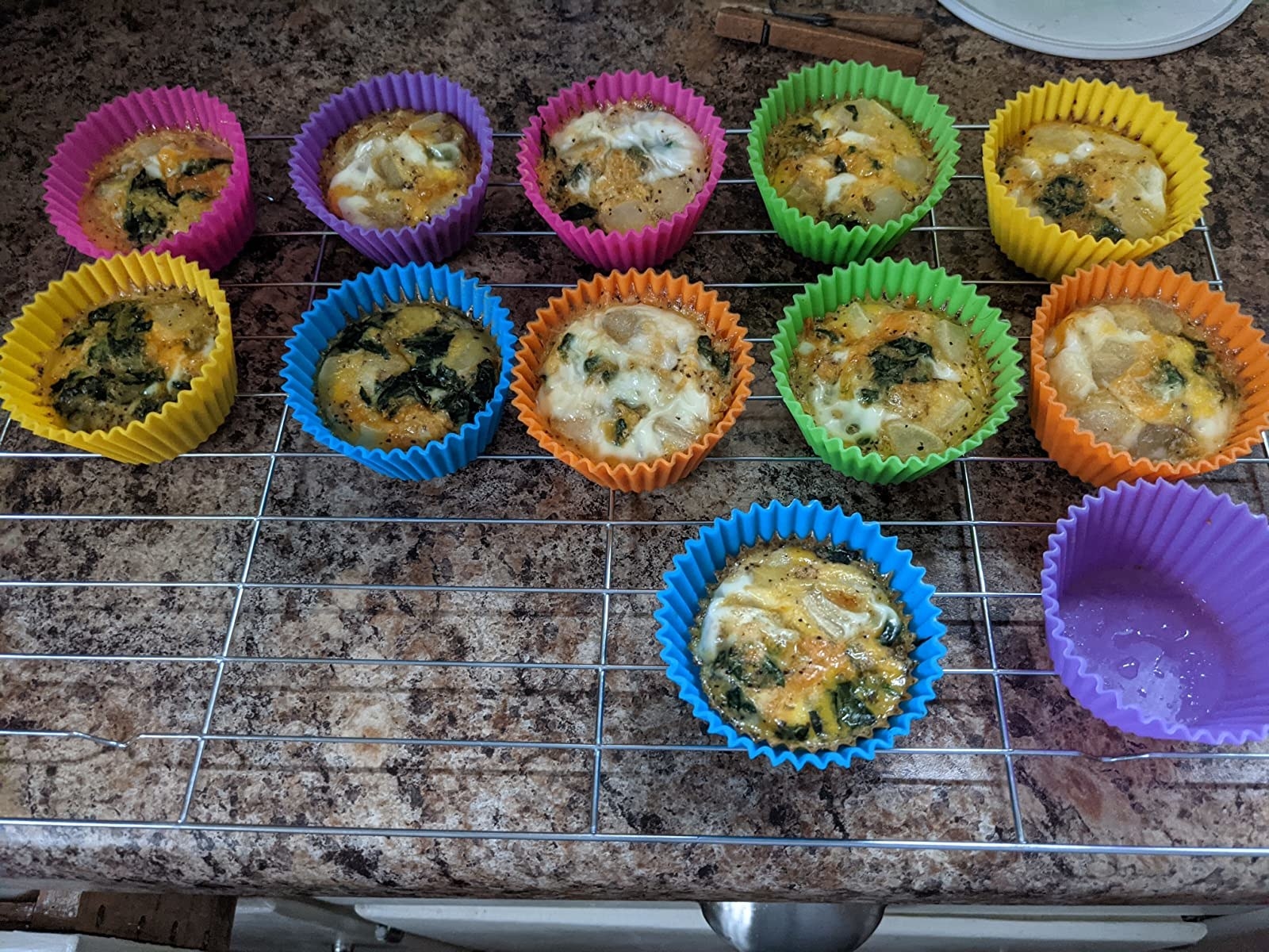 the pink, purple, blue, yellow, and orange silicone baking cups with muffins in them