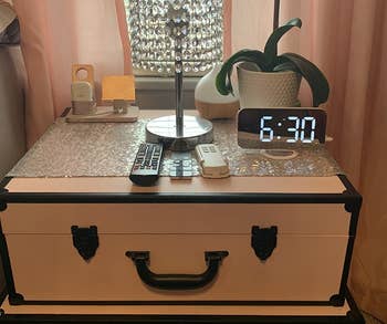 same digital alarm clock on stacked suitcase nightstand