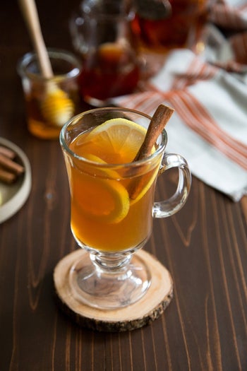 hot toddy made in a clear glass with orange slices and a cinnamon stick
