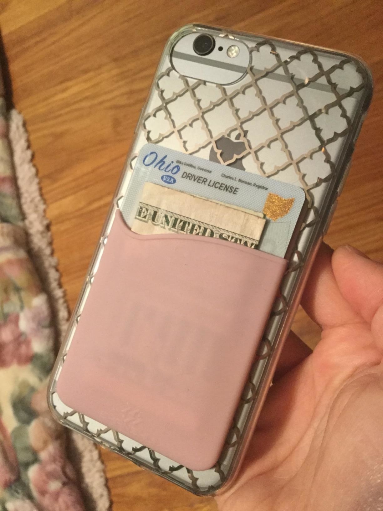 reviewer showing the phone with a pink card holder on the back with money and a license in it