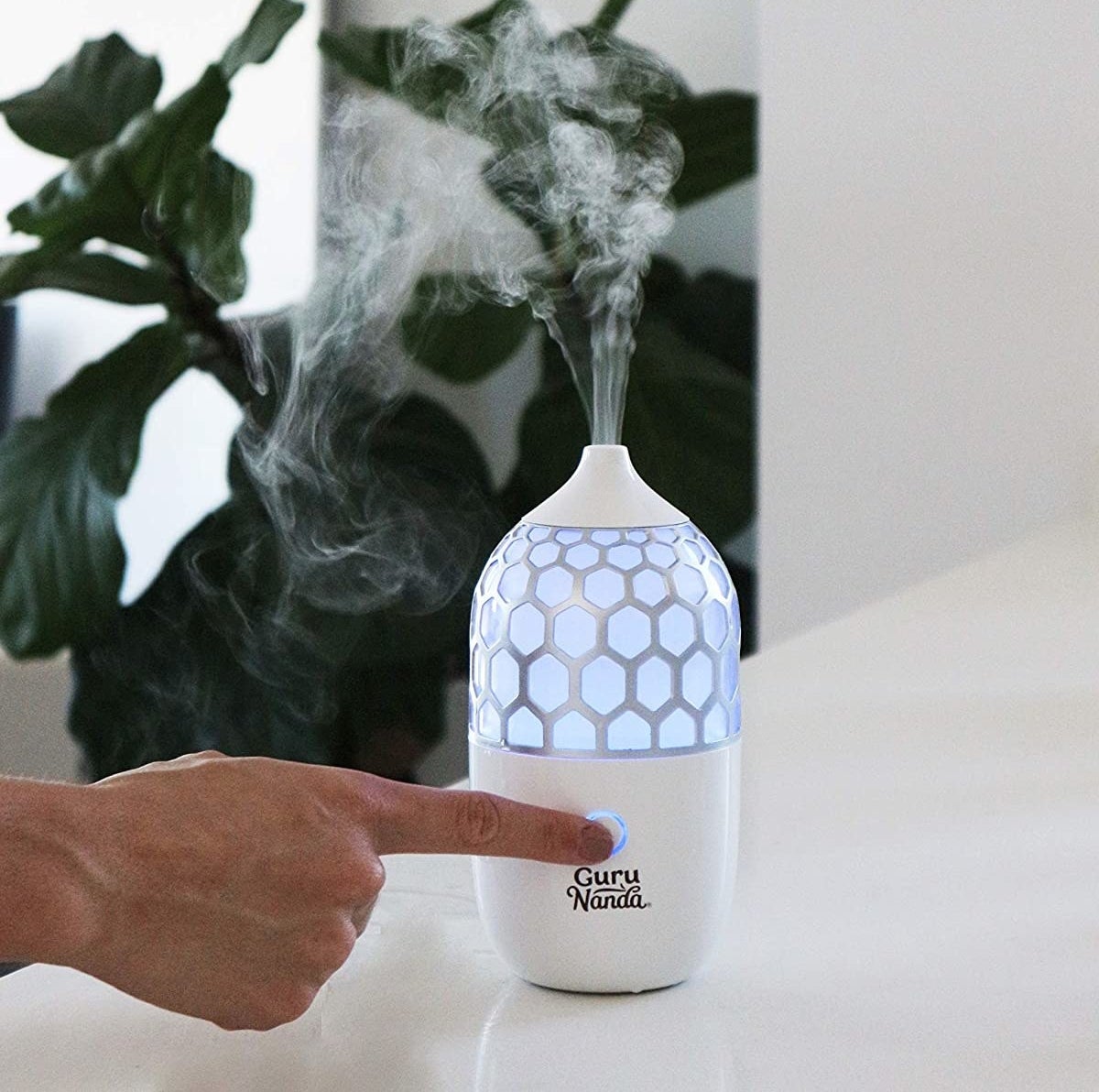 someone pressing the power button on the stylish oil diffuser