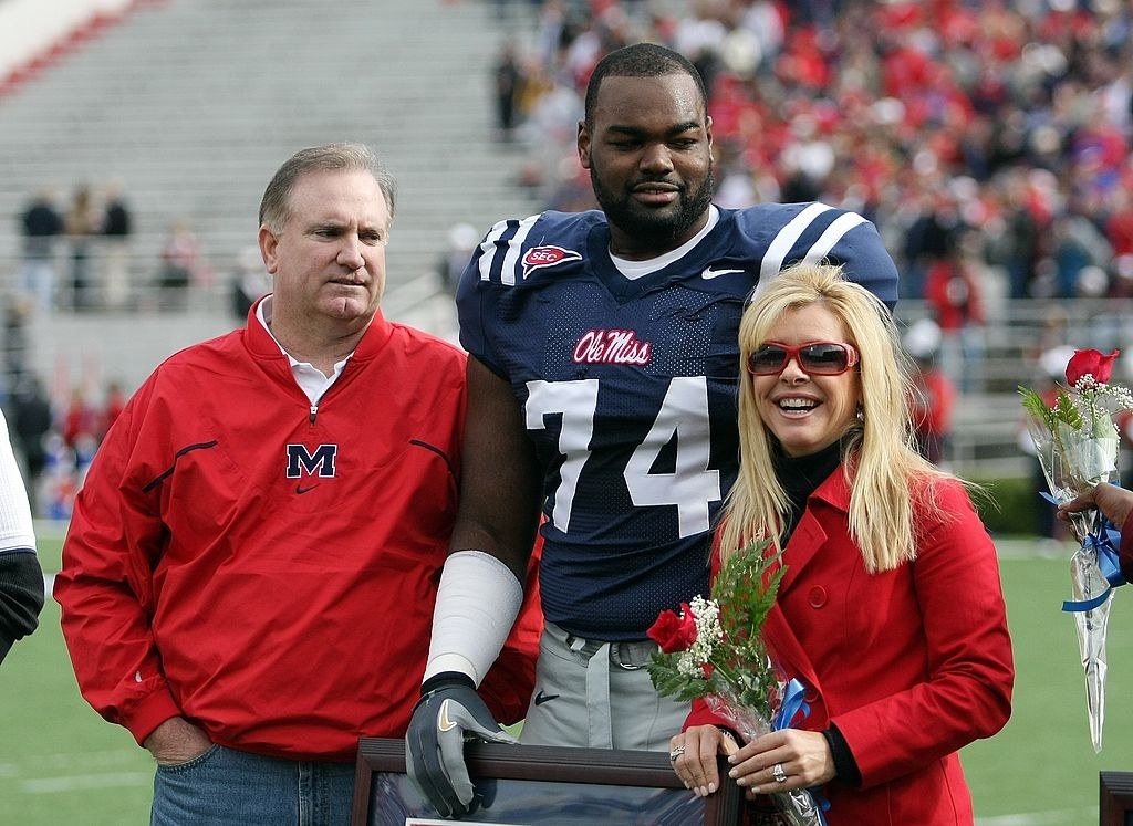 the real Oher, as an Ole Miss player, standing with his adoptive parents on the field