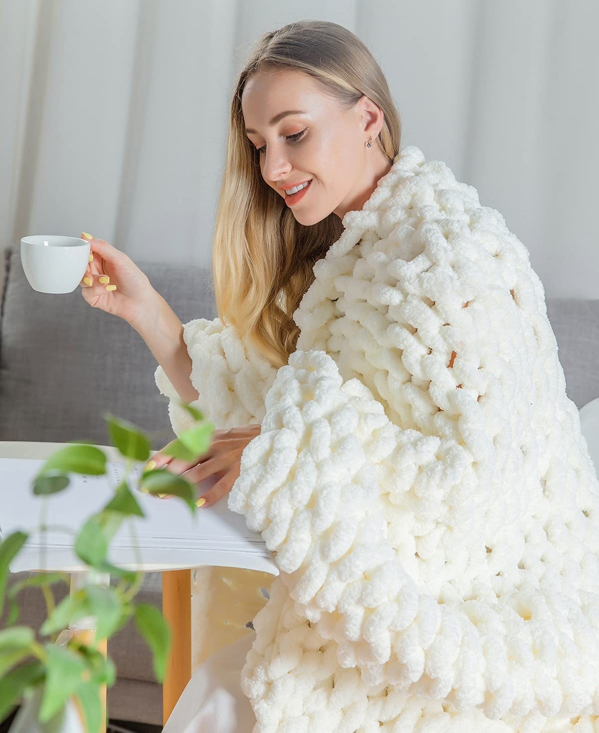 model wrapped in chunky blanket and reading