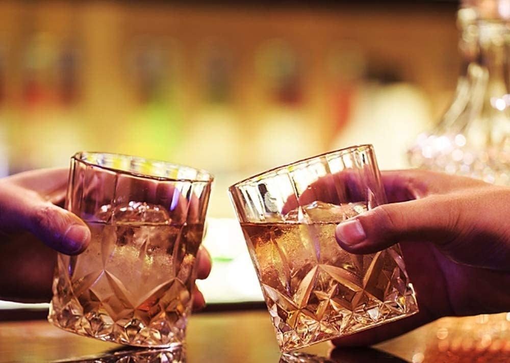 two people clinking a pair of crystal lowball glasses