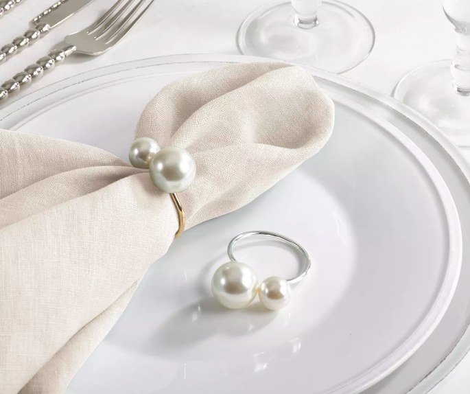 A napkin with the gold ring with the silver ring laying on the plate