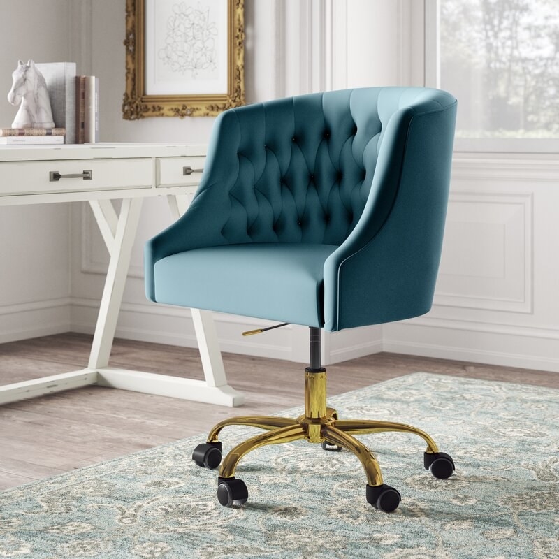 teal velvet chair on a gold stand with rolling wheels