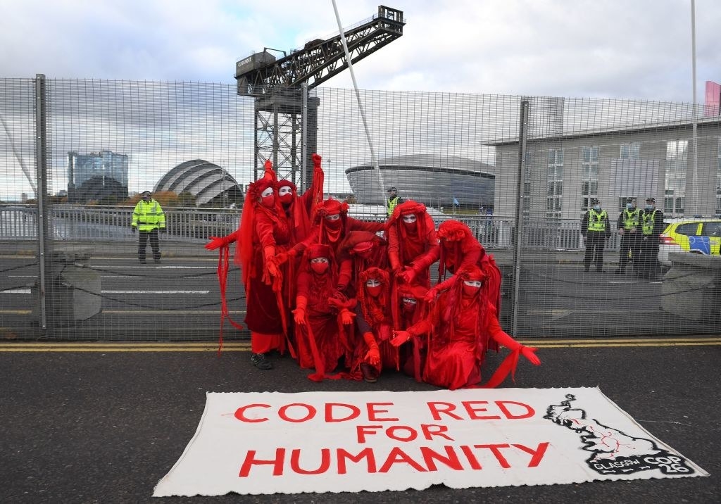 Protesters posing in front of a sign that says &quot;Code Red For Humanity&quot;