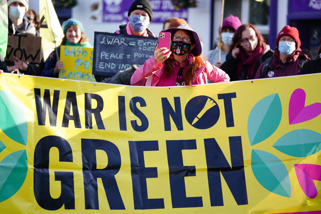 Protesters holding a sign that says &quot;War Is Not Green&quot;