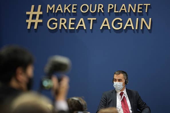 A sign that says &quot;#Make Our Planet Great Again&quot; above a person&#x27;s head