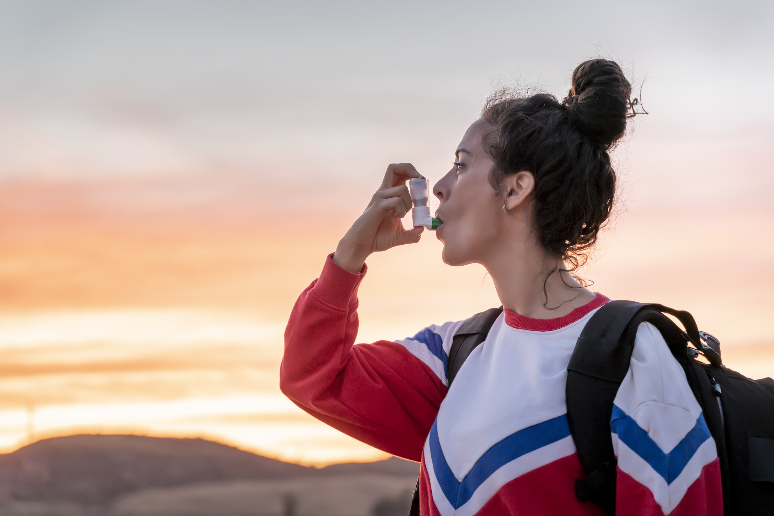 Woman using an asthma inhaler on a hike