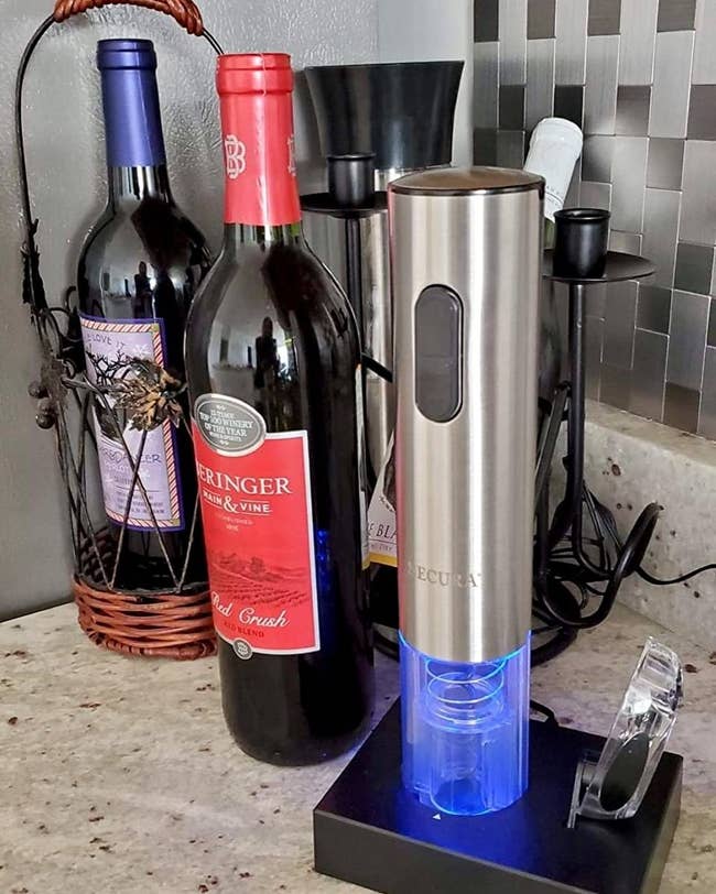a reviewer photo of the electric wine opener on the illuminated charging dock