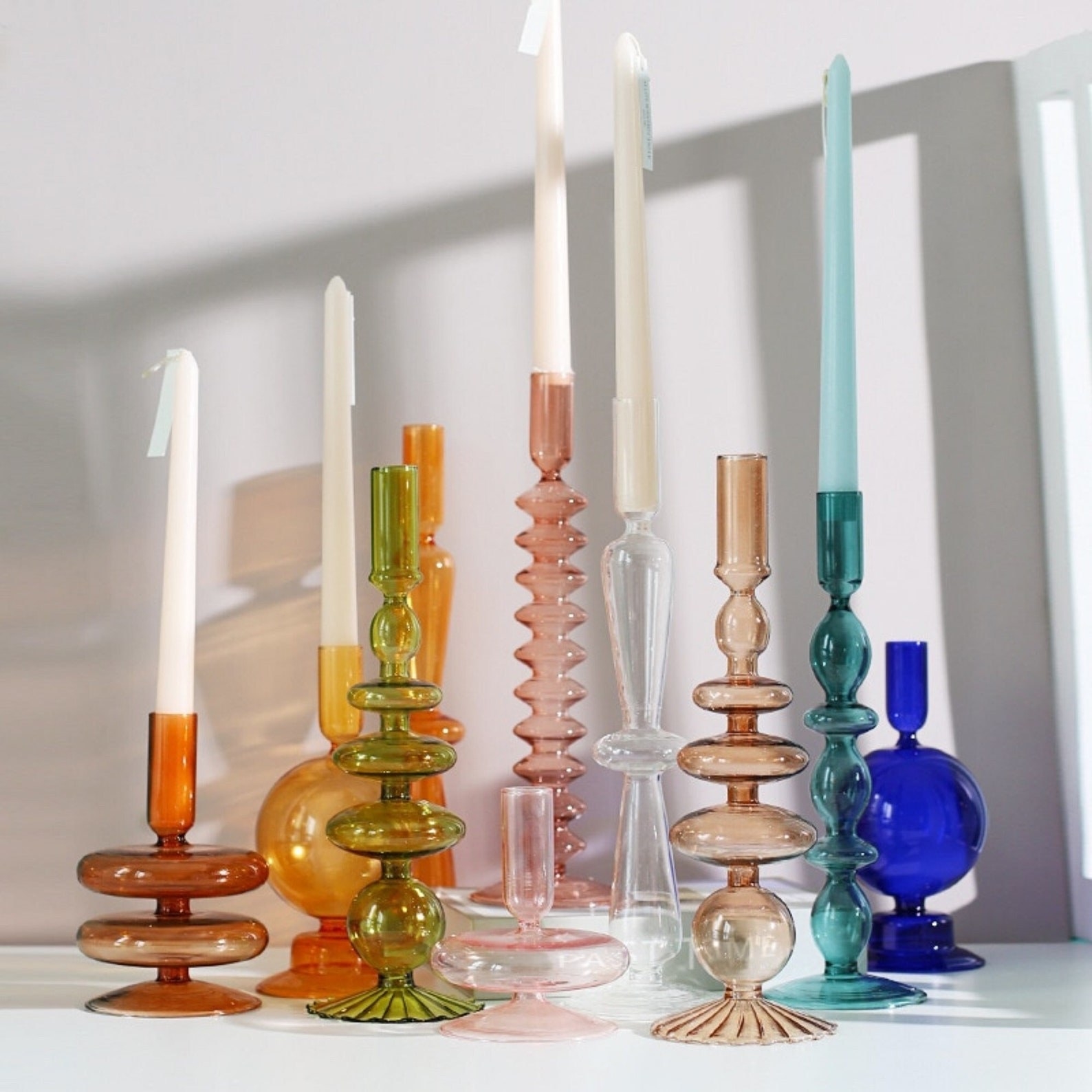 10 different candle holders in various shapes and colors. Five of them are holding white candles.