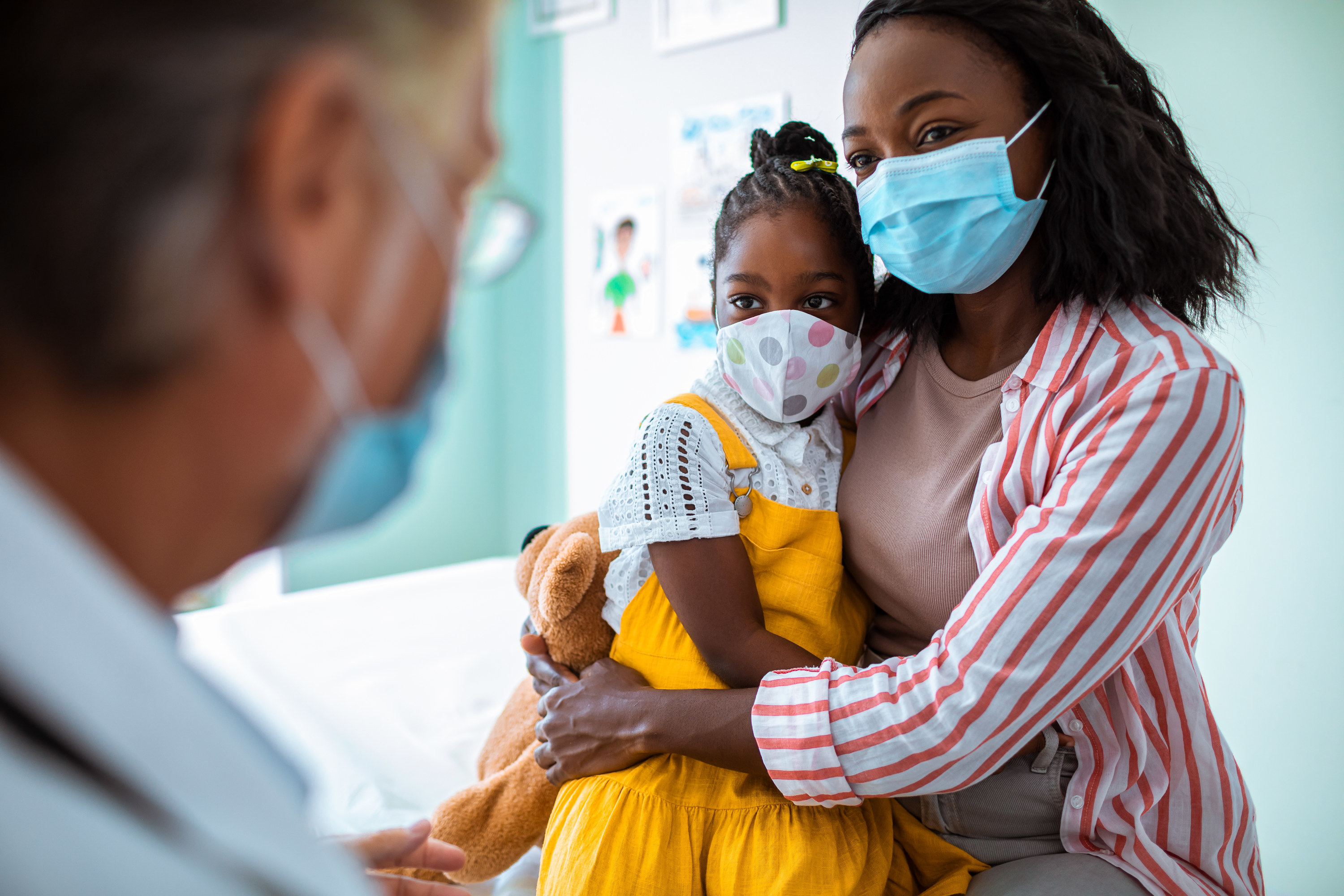 Woman holding her young daughter at a pediatric appointment