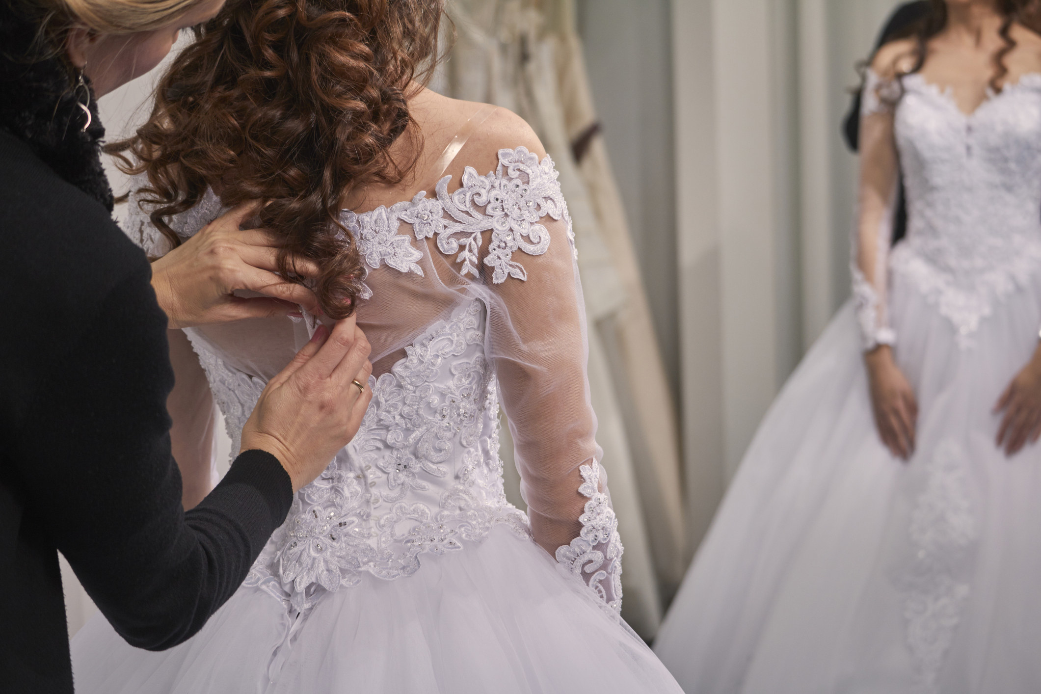A bride-to-be tries on a wedding dress at a boutique