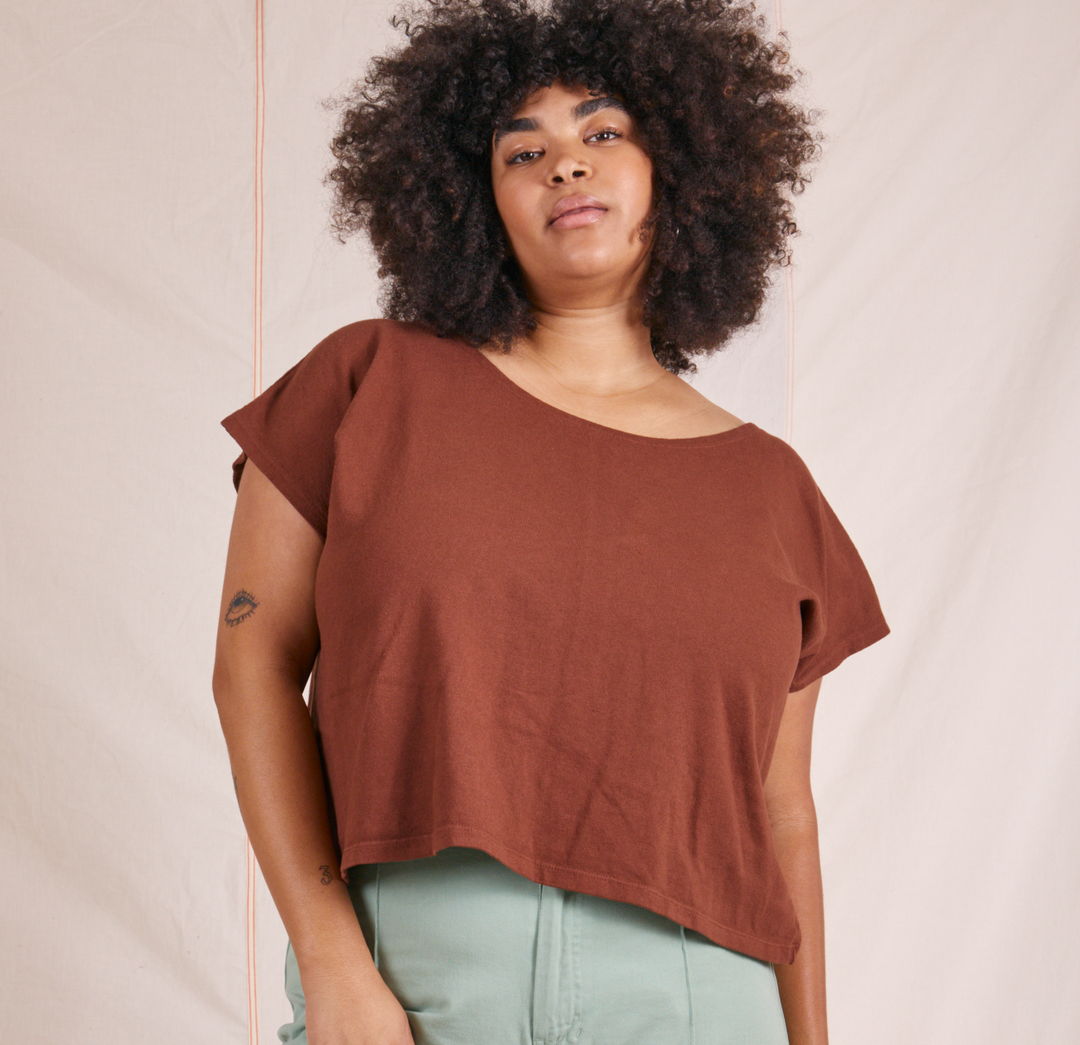 Model is wearing a rust colored tunic short sleeve top and pale green pants