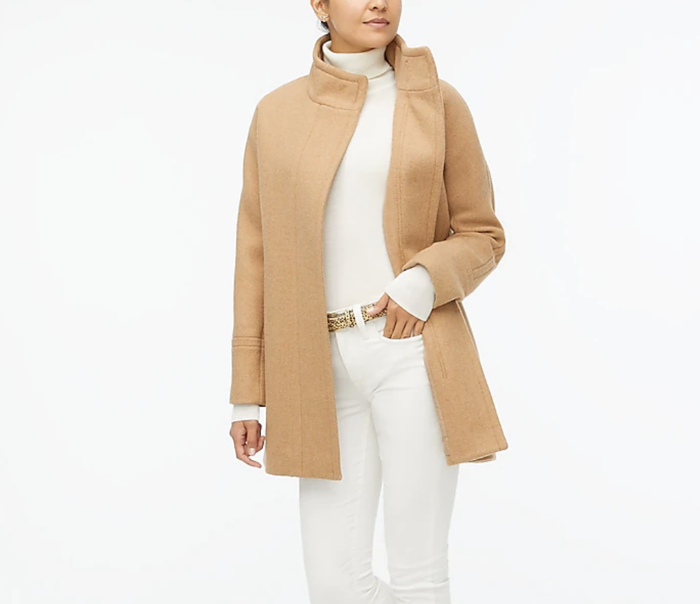 Model is wearing a beige coat over a white top and white pants