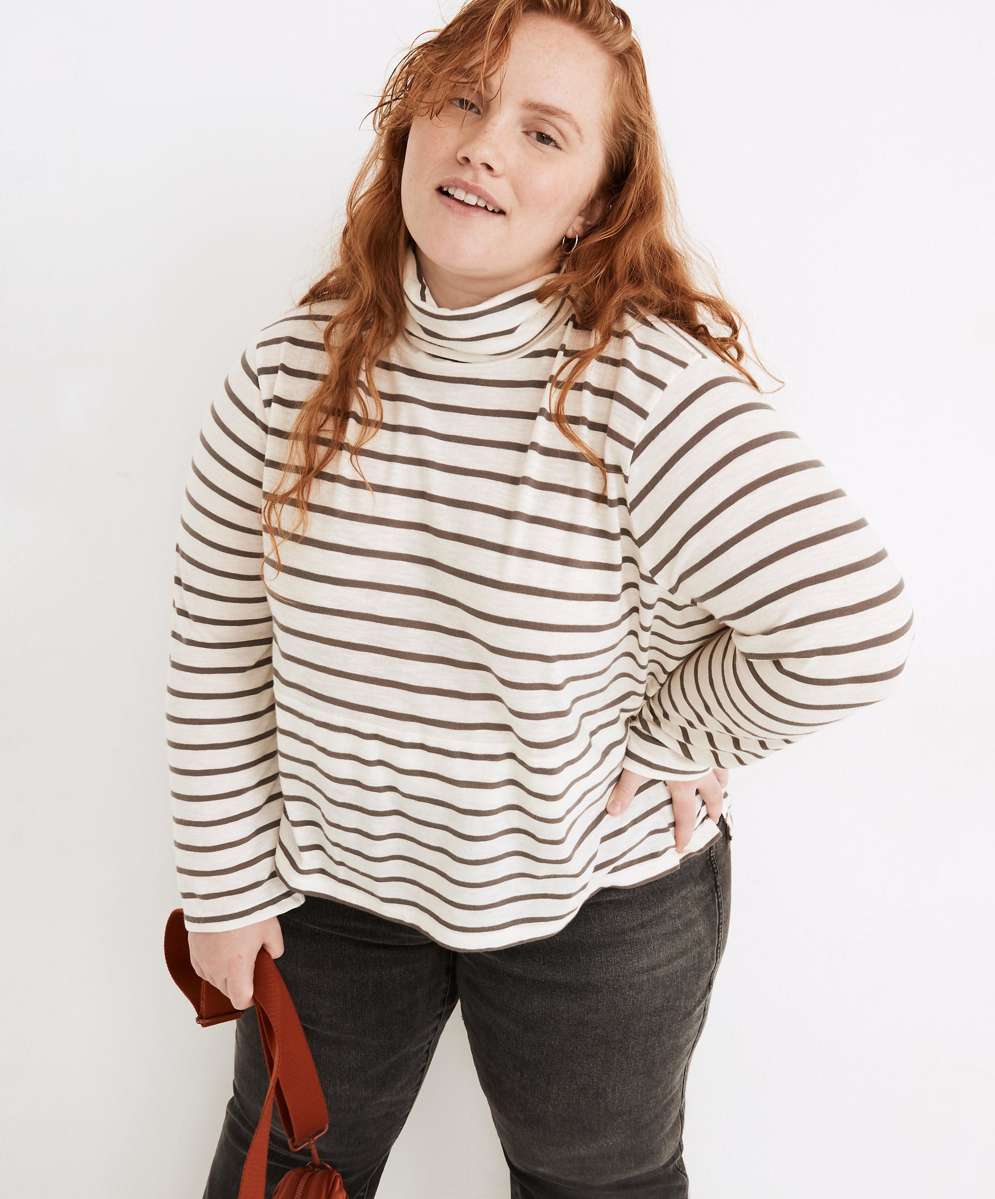 Model is wearing a white and brown striped turtleneck sweater and black denim jeans