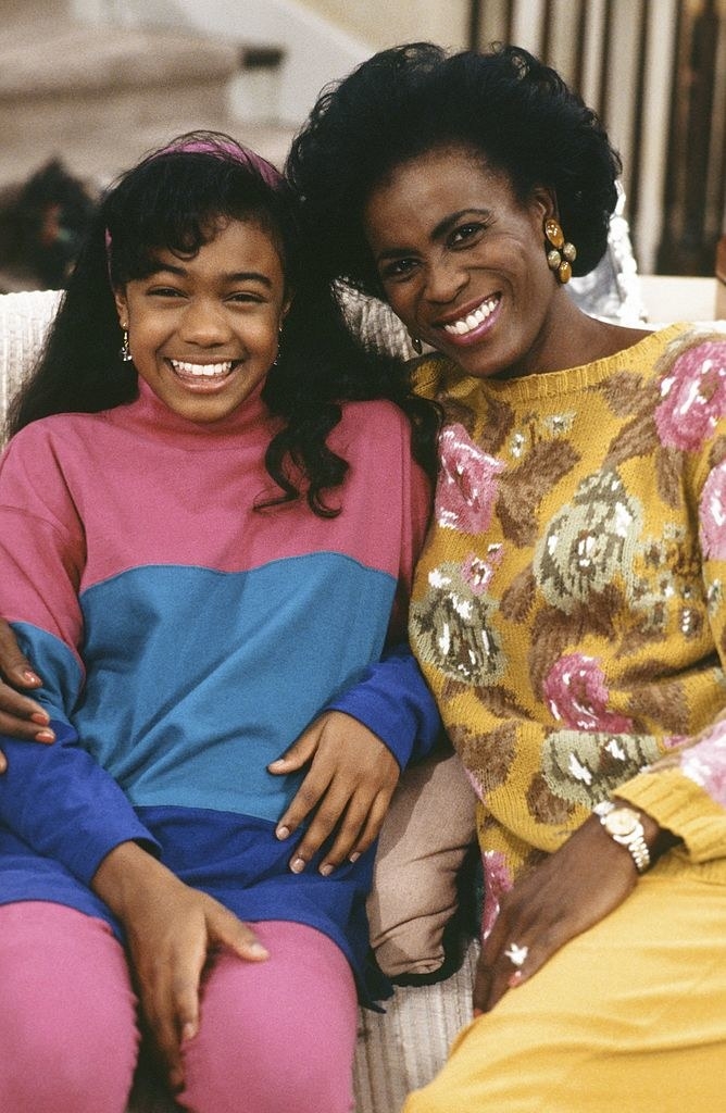 Tatyana Ali as Ashley Banks, Janet Hubert as Vivian Banks smile as they sit on a couch