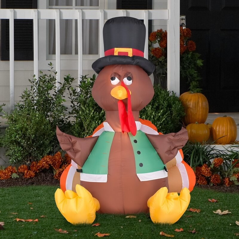 inflatable turkey wearing a hat and vest on a lawn